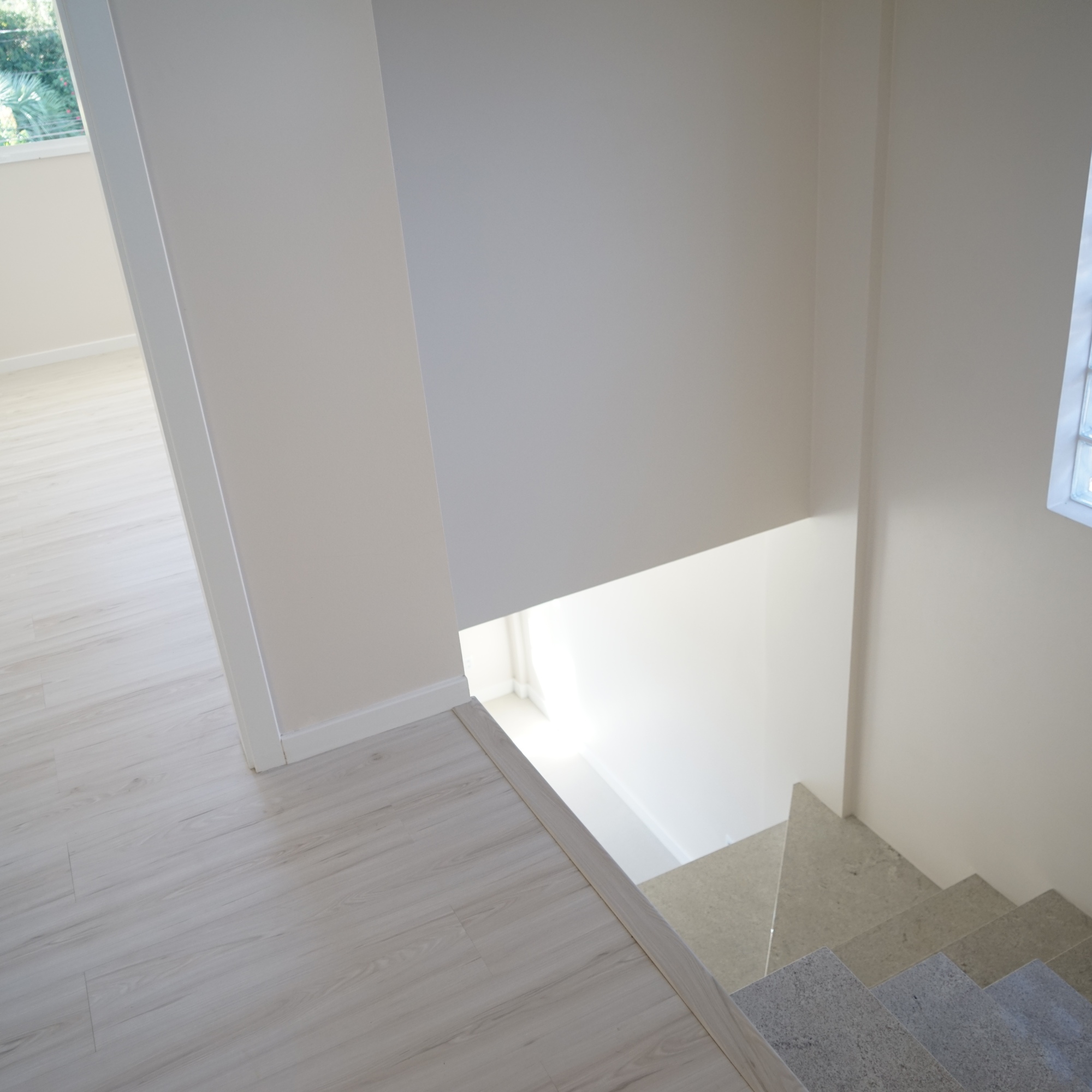 Escada em granito branco itaúnas, harmonizando com o piso laminado da área íntima.